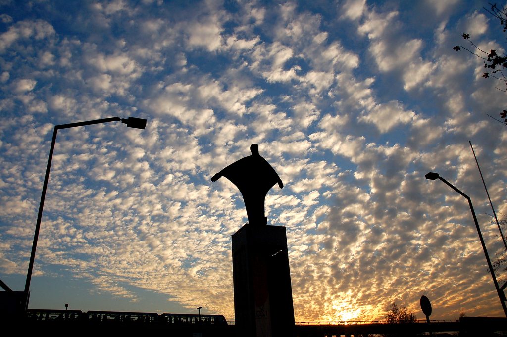 Estatua de Cristo de bronce en San Joaquín con cielo cubierto de nubes al atardecer